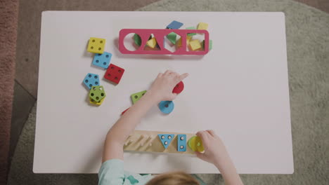 draufsicht auf ein kleines mädchen, das mit formen spielt, die sich in einer montessori-schule stapeln 1