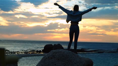 Woman-standing-on-rock-at-beach-4k