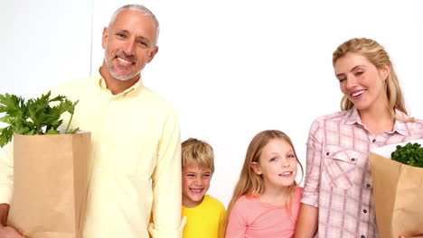 happy family smiling at camera with grocery bags