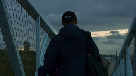 man with cap walks towards scheveningen beach during sunset, in 1000fps super slowmotion