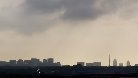 airplane taking off or landing over city skyline at sunset or sunrise