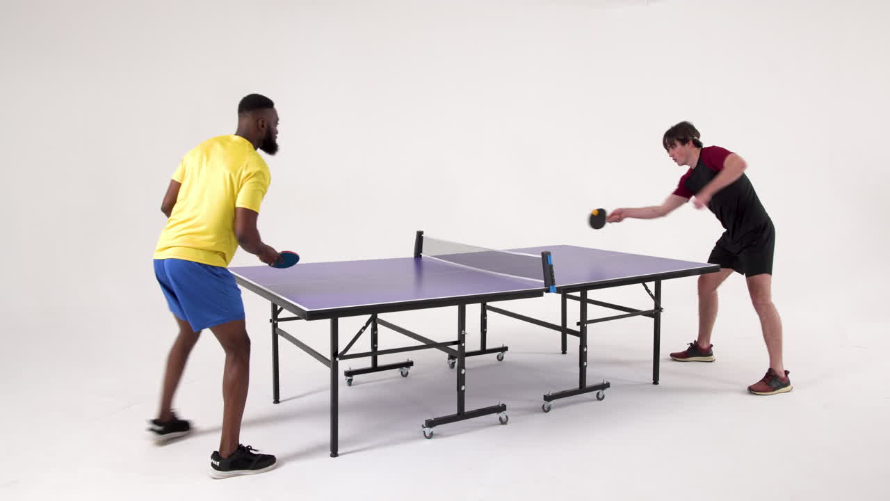 Playing table tennis, two men competing in fast-paced match indoors