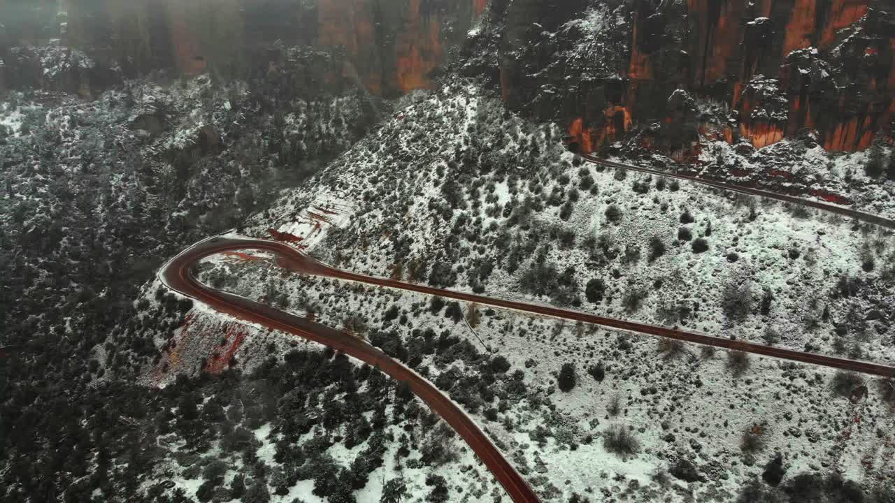 Aerial view of a winding road through a snowy canyon