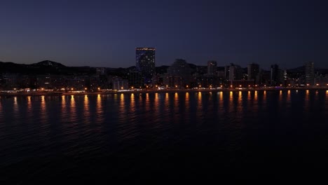calp city waterfront with illuminated buildings and estimar hotel reflecting at night, spain.