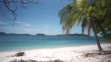 Imágenes-De-Playa-De-Arena-Blanca-Con-Aguas-Turquesas,-Palmeras-E-Islas-En-La-Distancia