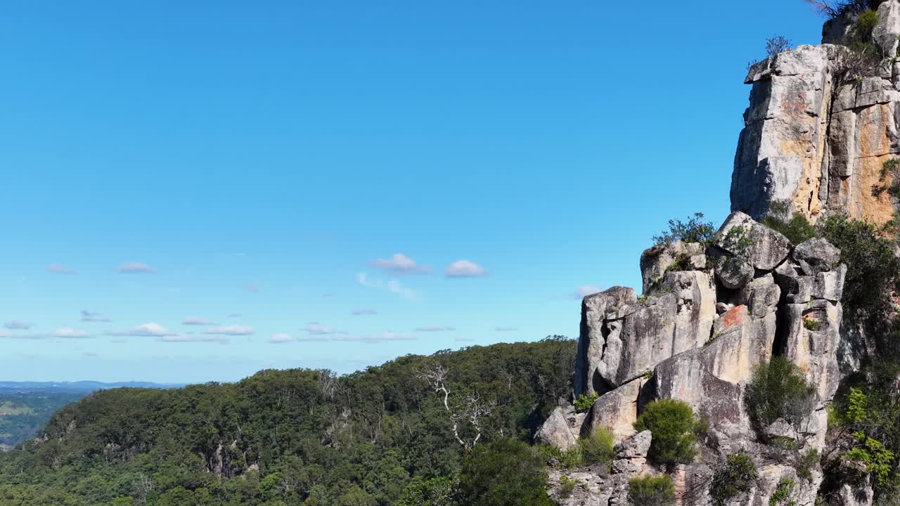 Aerial footage showcasing the majestic Nimbin Rocks under clear blue skies, highlighting natural beauty and rugged landscapes