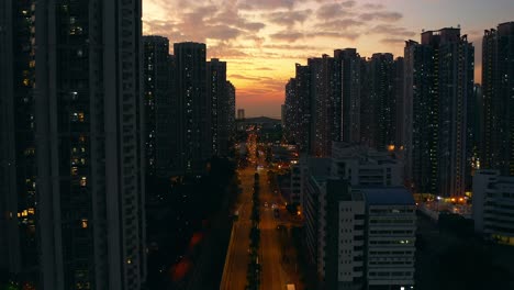 drone shot traveling backward above a busy street in an urban area full of public housings buildings during sunset
