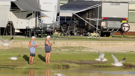 two people fishing as a bird flies past