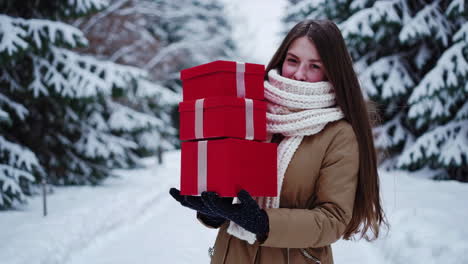 young woman carrying christmas gifts in a snowy winter forest