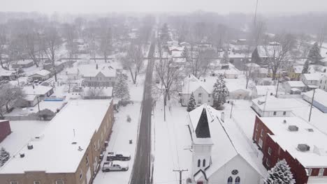 downtown of small town in usa during snowfall, aerial ascend view