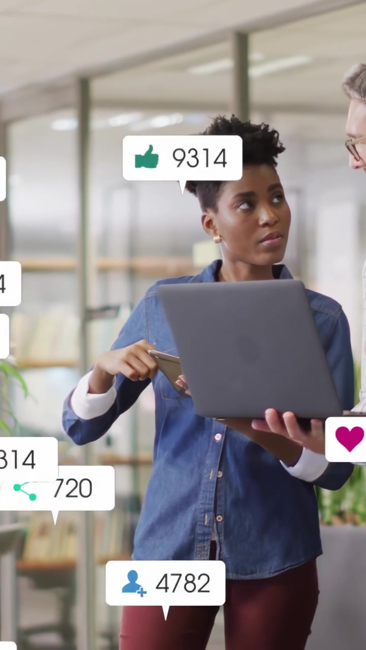 Woman tapping phone and man pointing laptop in office sparking live alerts raising marketing KPIs