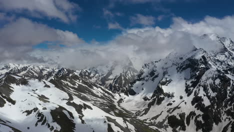 vuelo aéreo a través de nubes montañosas sobre hermosos picos nevados de montañas y glaciares.
