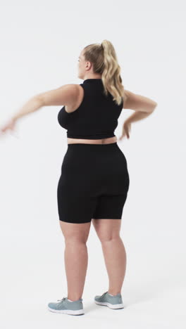 vertical video: stretching arms, plus size woman in athletic wear embracing body positivity