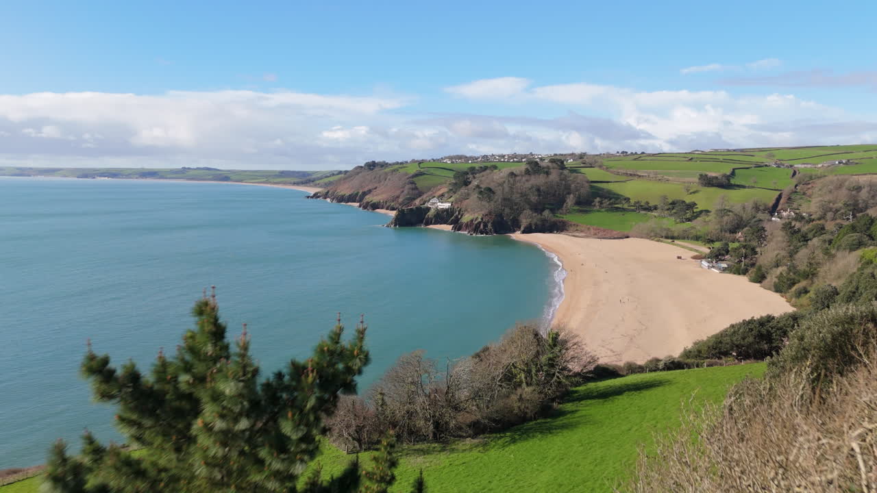 el dolly aéreo sobre las copas de los árboles revela la pintoresca playa de blackpool sands, en el sur de devon, reino unido.