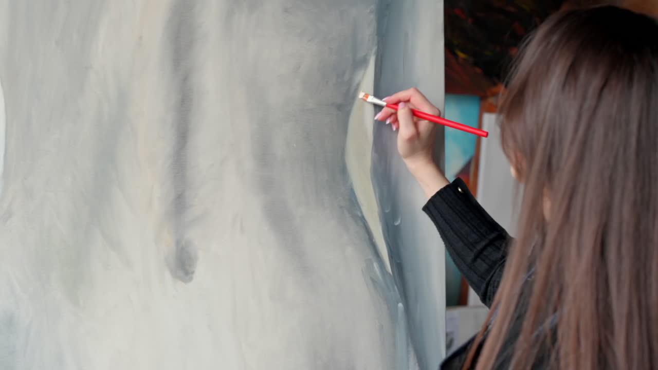 Woman painter wearing black clothes painting woman model at a workshop