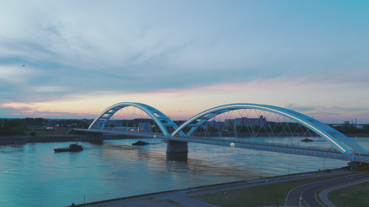 강 을 가로지르는 현대적 인 아치 다리 의 해 가 지는 모습