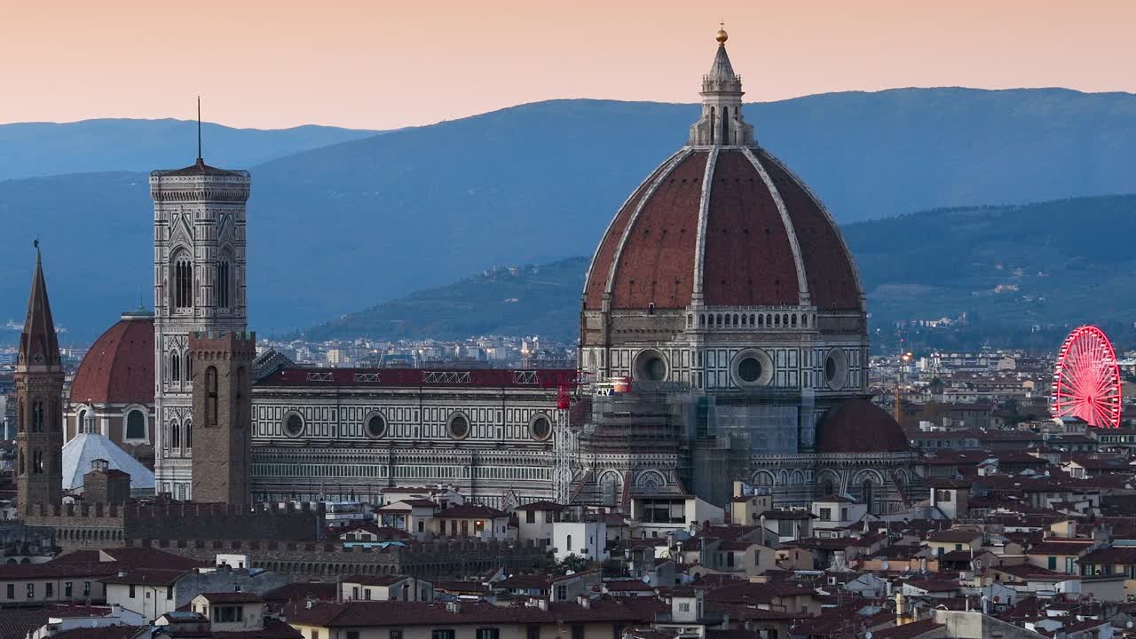 피렌체의 산타 마리아 델 피오레 대성당은 미란젤로 광장에서 볼 수 있으며, 왼쪽 배경에는 조명된 페리스 이 있습니다.