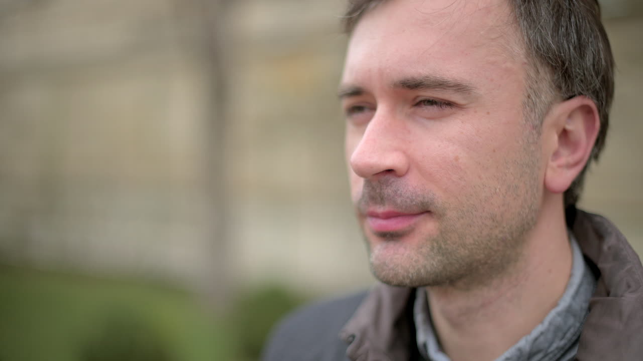 Man in brown coat drinking a pink beverage outside