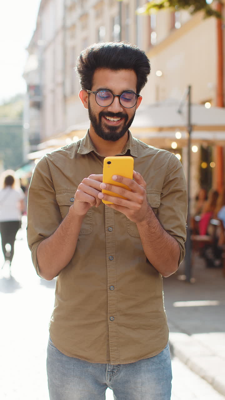 Indian man use smartphone typing text messages browsing internet finishing work chatting online