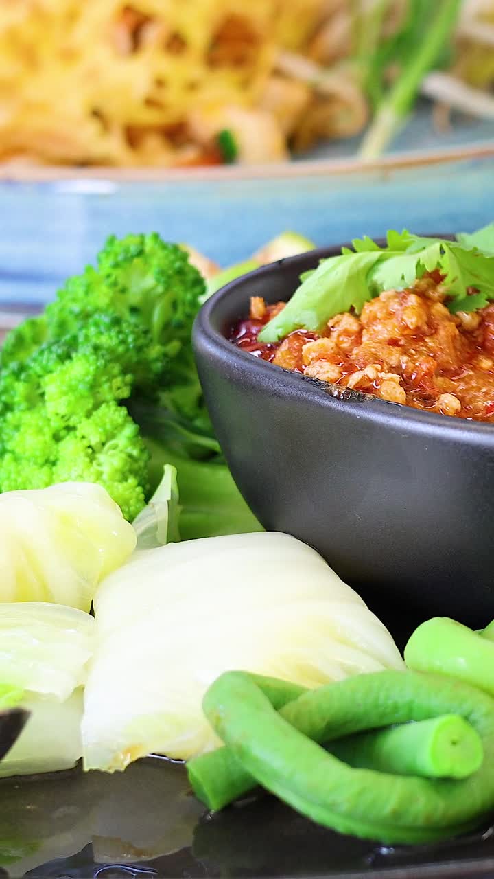 손으로 채소를 매운 태국 소스에 담아 넣는 것