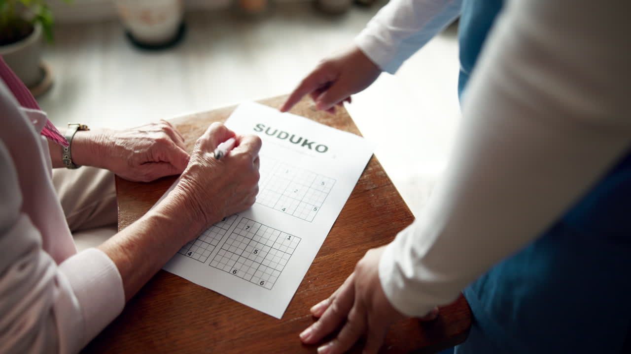Senior woman playing sudoku with assistance