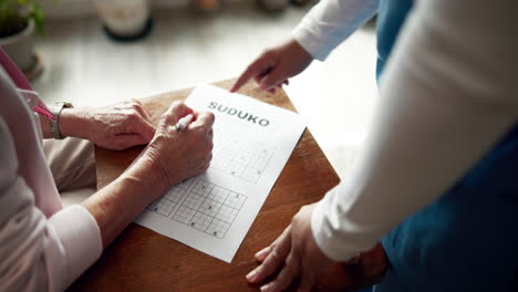 senior woman playing sudoku with assistance