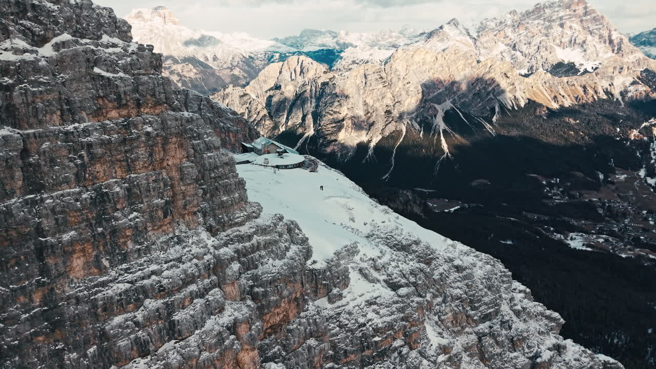 Drone-luftoptagelse af snedækkede klipper og tinder i Dolomitterne under en skyet himmel