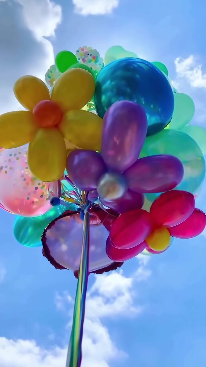 Palloncini a forma di fiore colorati che fluttuano contro un cielo blu brillante