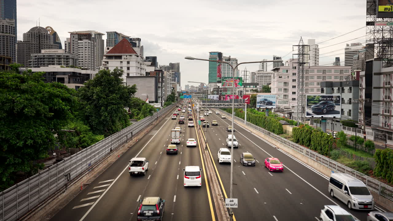 Bridge view over expressway with traffic in Bangkok surrounded by buildings