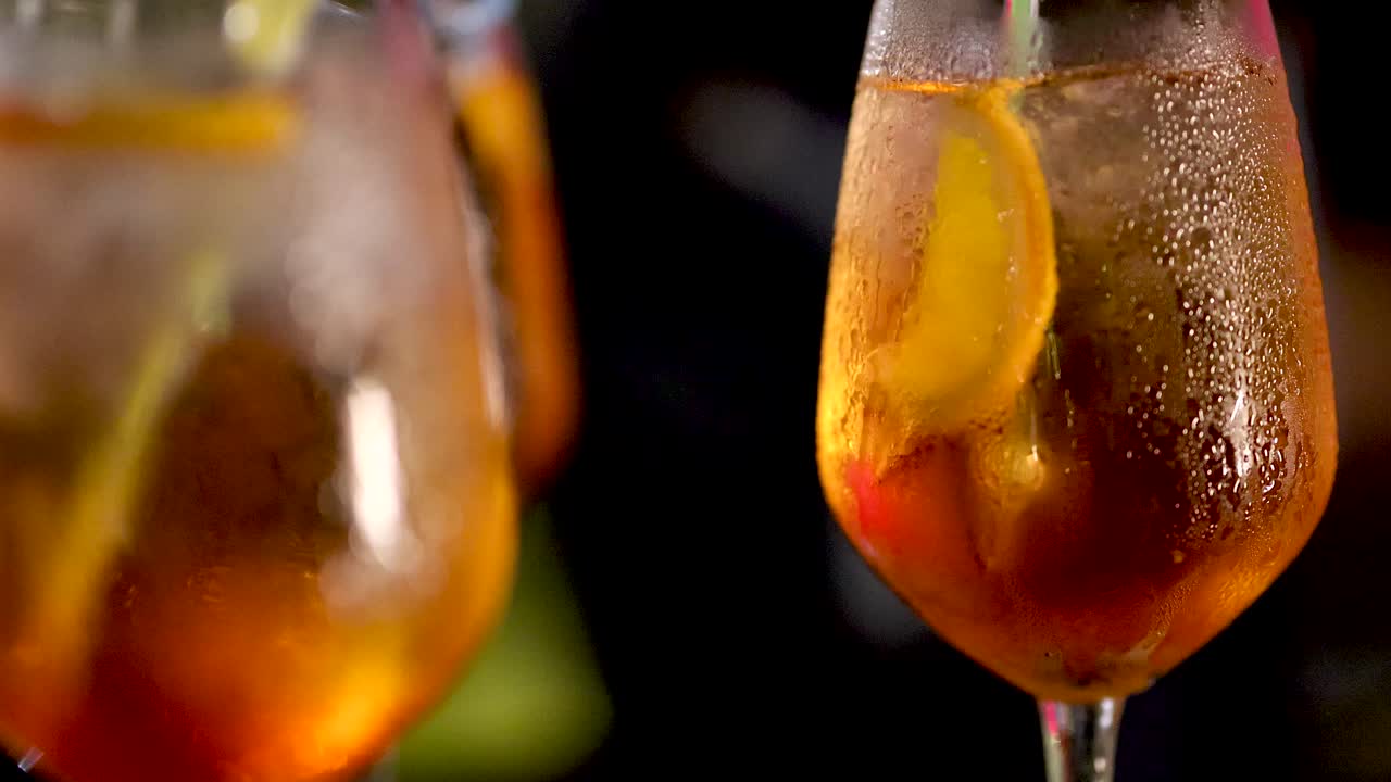 Chilled Negroni cocktail in stemmed glass, lemon slice, ice, dramatic lighting, slow camera movement
