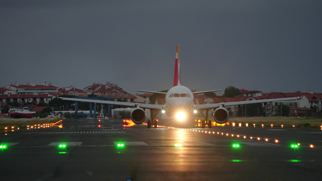 Passenger airplane slowly taxiing along runway with navigation lights on during cloudy evening