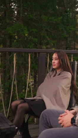 gentleman and lady relax on terrace at dusk. young family unwinds in cozy armchairs during environmentally conscious retreat. snug vacation during briskness of autumn