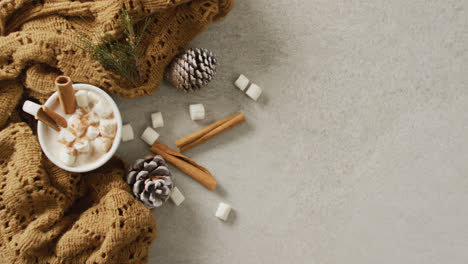 video of cup of hot chocolate with marshmallows and warm blanket over grey background