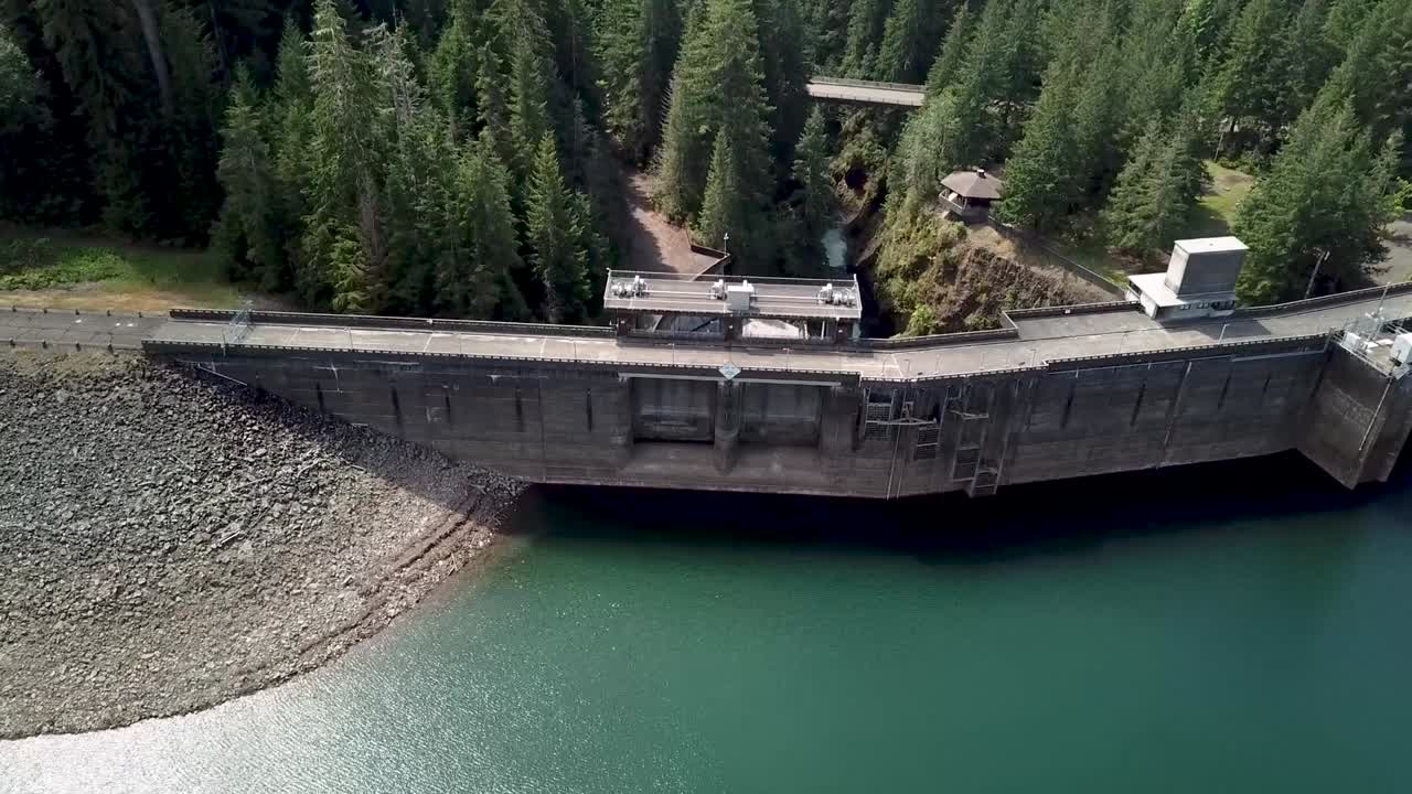 volando hacia la presa de wynoochee con un lago tranquilo y exuberantes árboles coníferos verdes en las montañas del norte de montesano, estado de washington, estados unidos