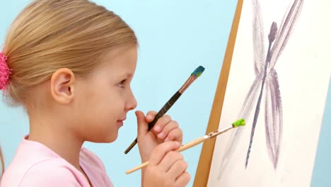 smiling girl holding two paintbrushes