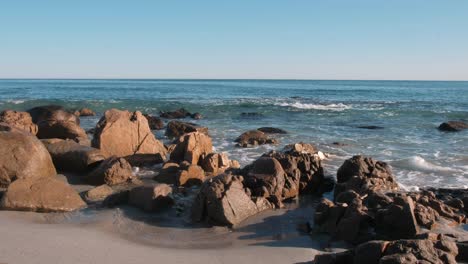 olas rompiendo en una playa con rocas en primer plano