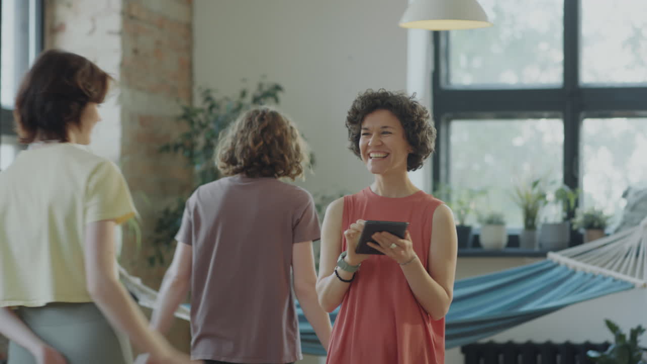 Yoga Teacher Using Tablet and Greeting Students