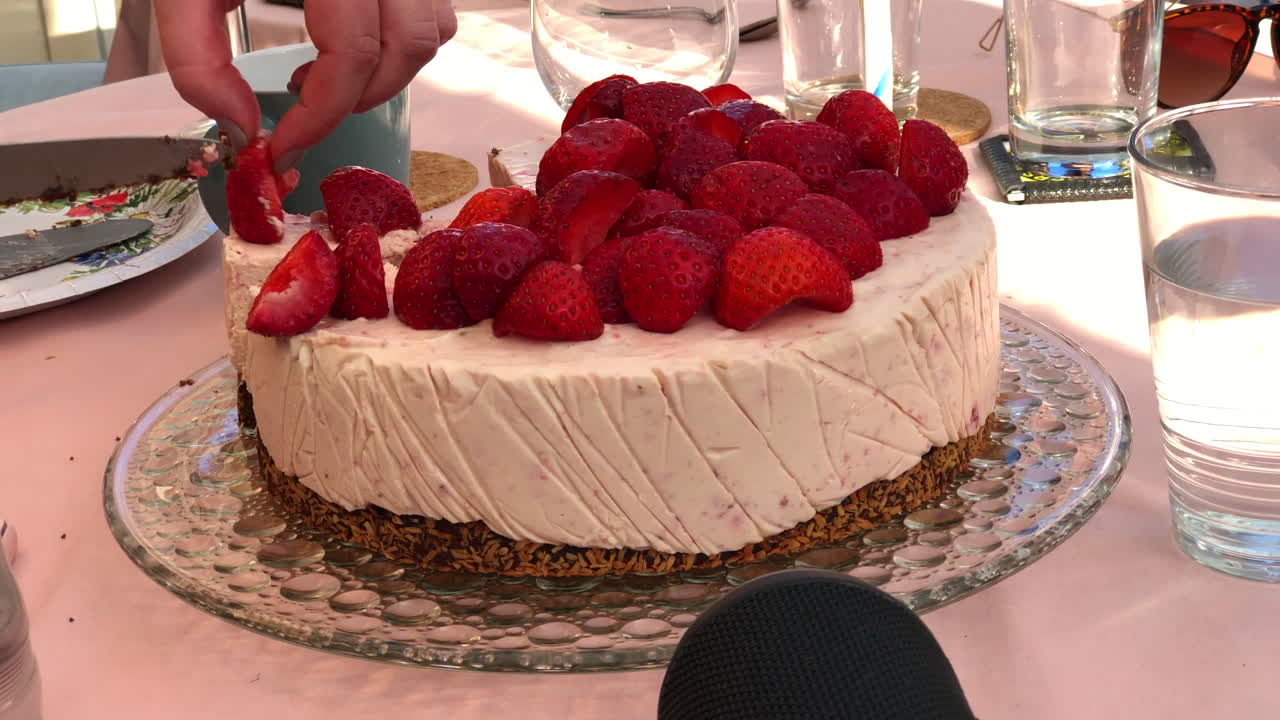 Taglio di torta alle fragole all'aperto con coltello d'argento