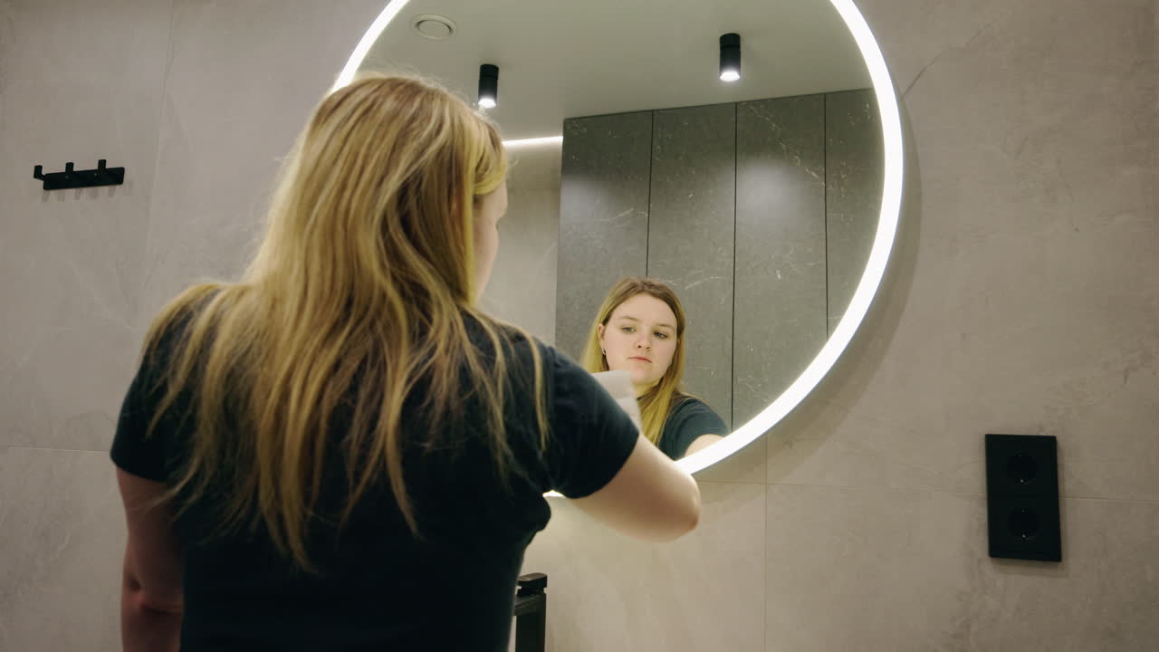 Woman Cleaning a Bathroom Mirror