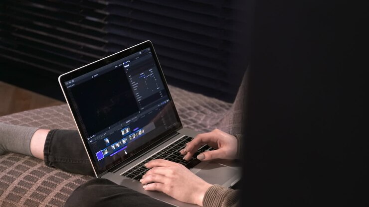 Young content creator girl is on her laptop sitting on the sofa. Working with video from home