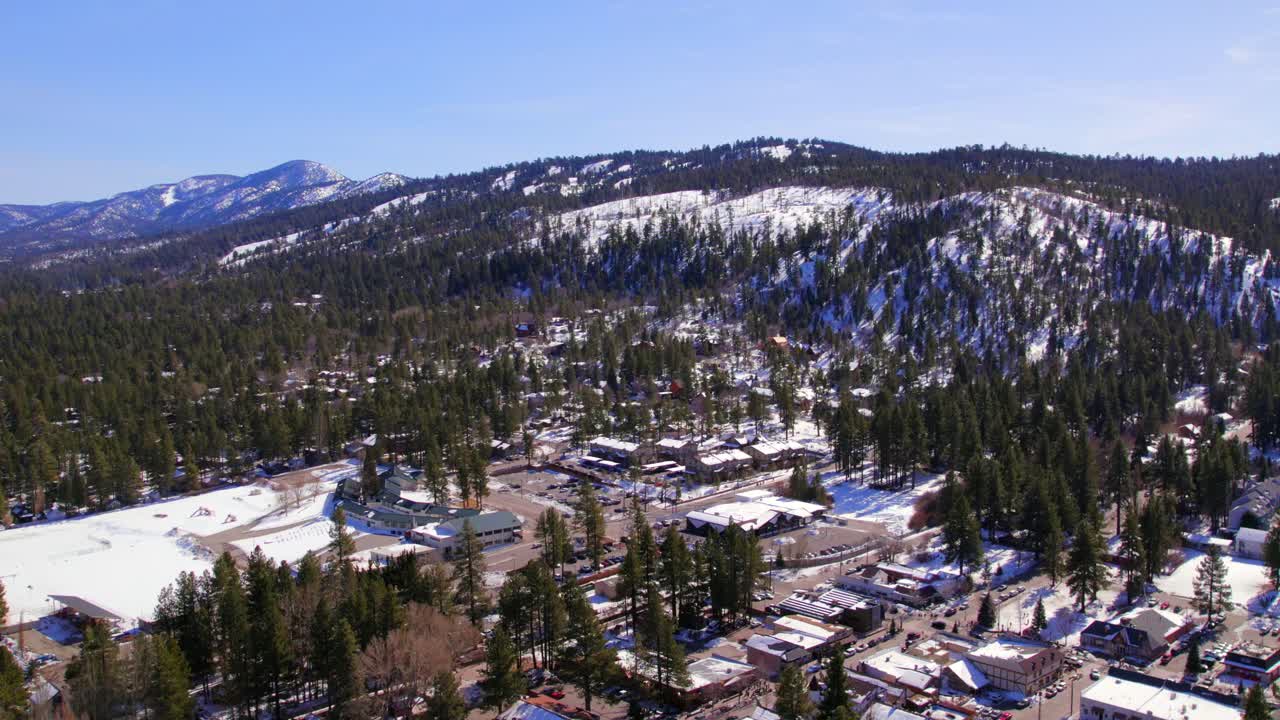 paralaje a través de la montaña big bear california capturando la impresionante vista aérea con exuberante bosque verde y techos cubiertos de nieve
