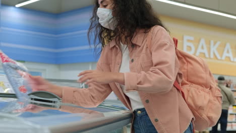 женщина покупает замороженные продукты в супермаркете
