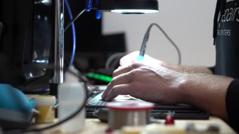 Man-fixing-up-laptop-micro-soldering-under-microscope