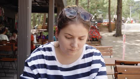 A-close-up-shot-of-a-30-year-old-woman-reading-a-menu-in-a-restaurant