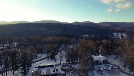 low altitude flyover of mansion an winter hills with bright evergreens and blankets of snow