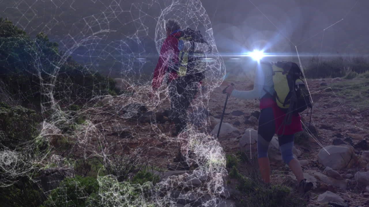 mature couple hiking rocky trail with backpacks, showing technology mesh overlay and lens flare