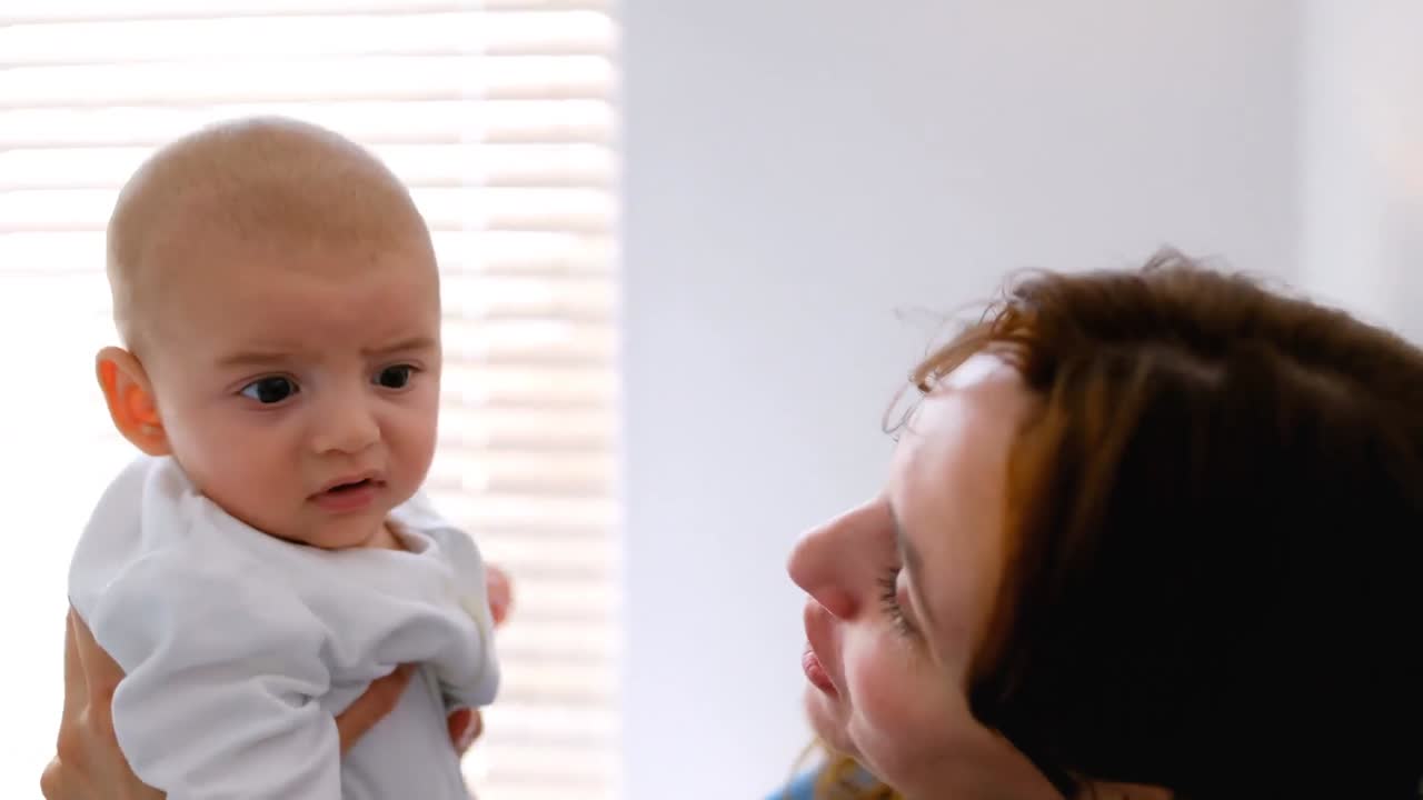 집 에서 아기 를 안고 키스 하는 젊은 어머니 4k