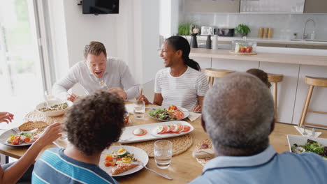 Familia-De-Raza-Mixta-Multigeneracional-Comiendo-Comida-Alrededor-De-La-Mesa-En-Casa-Juntos