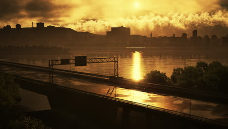 sunset over a city with a bridge crossing a river