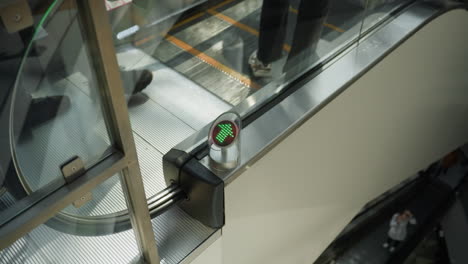una vista en primer plano capturando una escalera mecánica en un centro comercial con personas que bajan. el enfoque está en los detalles mecánicos de la escalera y los reflejos de las personas en la superficie metálica